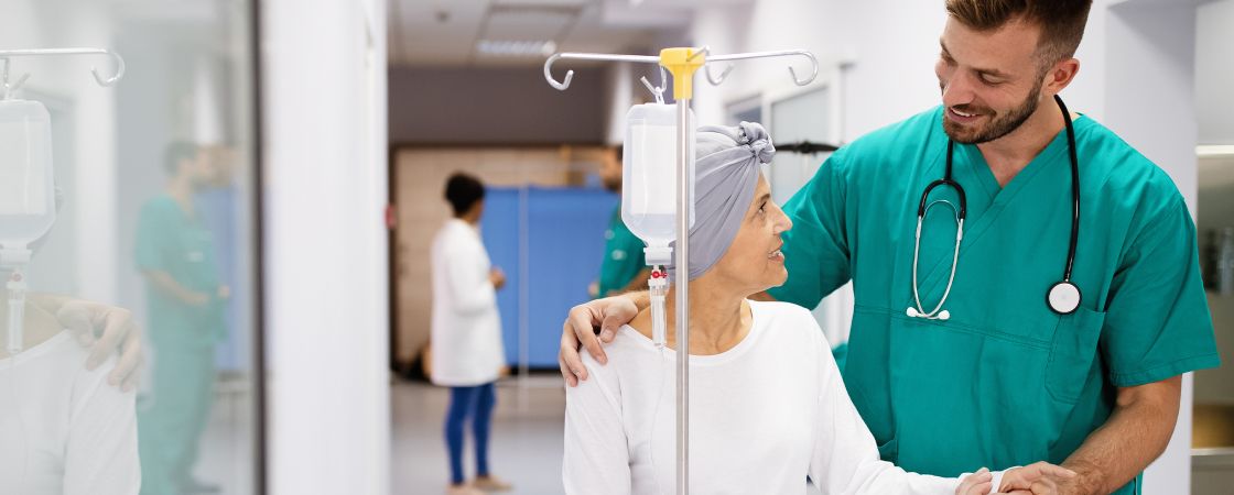 Nurse with arm around cancer patient in hospital hallway