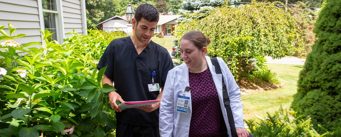 Two nurses looking at a folder as they walk outside