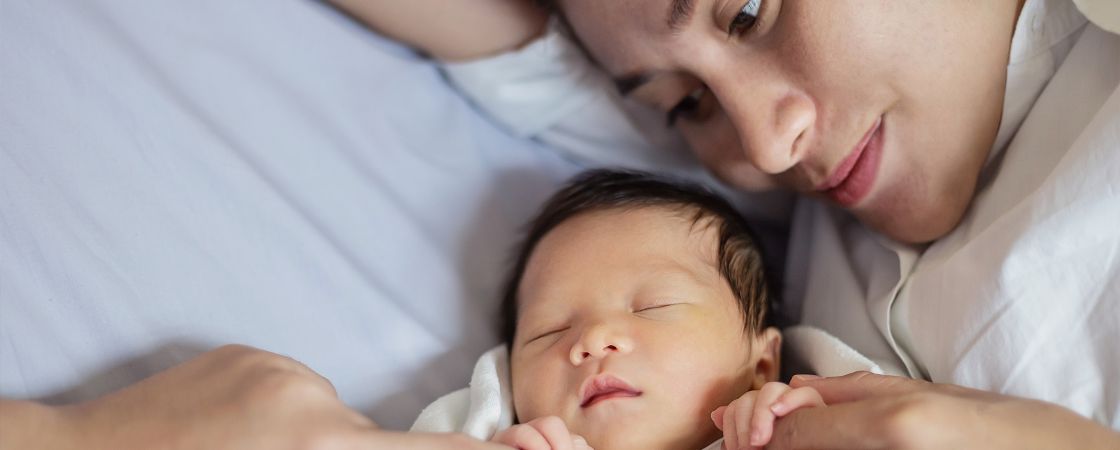 Mom holding infant baby on bed