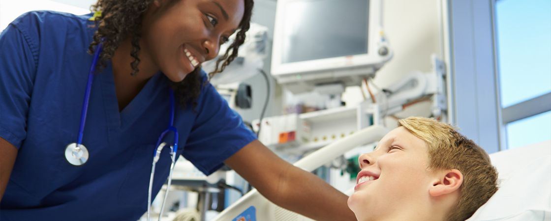 Nurse talking to young patient in hospital bed