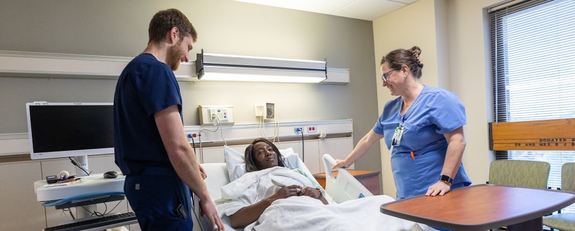 Nurses speaking to patient in hospital bed