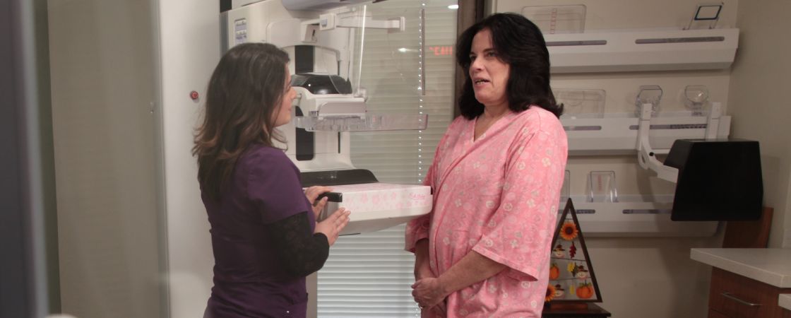 Nurse and patient speaking next to mammogram machine