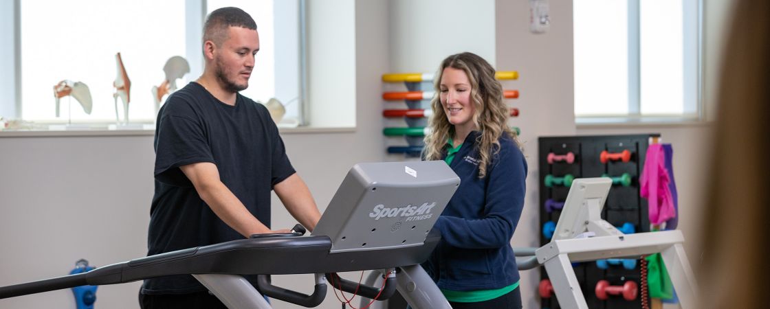 Patient on treadmill with Bristol Health employee assisting