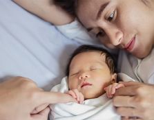 Mom holding infant baby on bed
