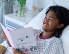 Girl in hospital bed reading a card