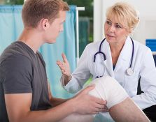 Doctor talking to patient with bandaged knee