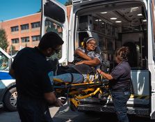 EMT bringing person on a stretcher into an ambulance