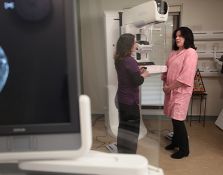 Nurse and patient speaking next to mammogram machine