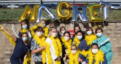 Group of Bristol Health employees smiling outside with balloons and boas 