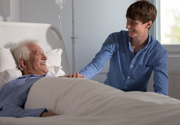 Junior volunteer speaking to elderly patient at hospital