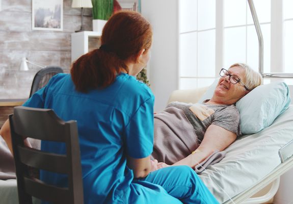 Nurse speaking to patient in hospital bed
