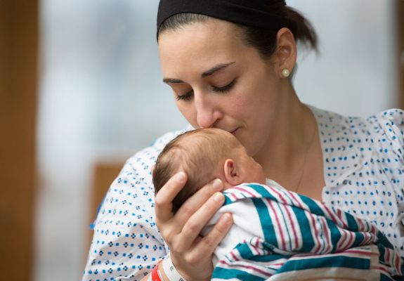 New mother kissing newborn on the forehead