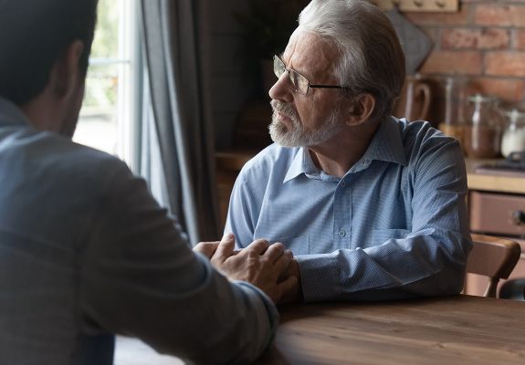 Son offering comfort to his father, extending his hands toward him