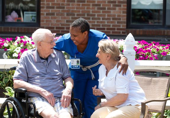 Nurse with arms around two patients