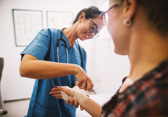 Doctor wapping patient's wound on hand