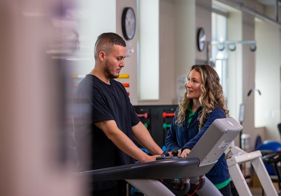 Employee assisting patient on treadmill