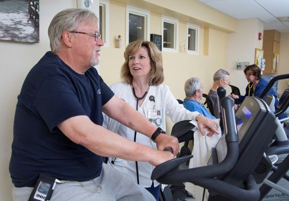 Doctor speaking to patient on exercise bike