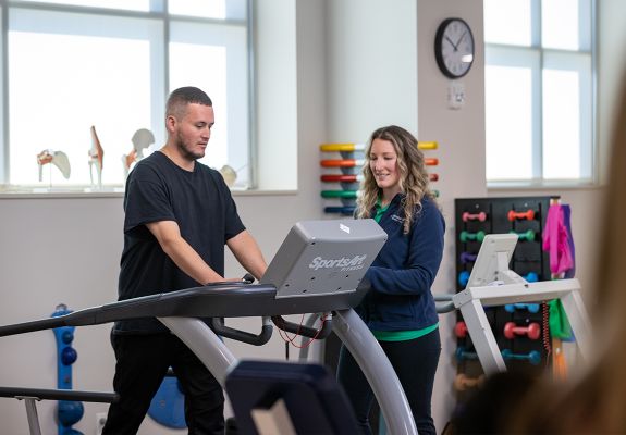 Bristol Health employee assisting patient on treadmill