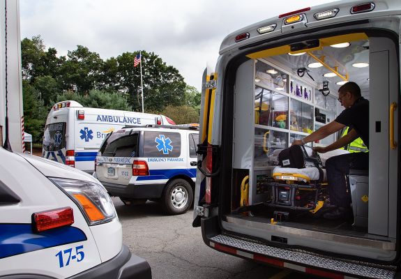 EMT in the back of an ambulance in a parking lot with other ambulances