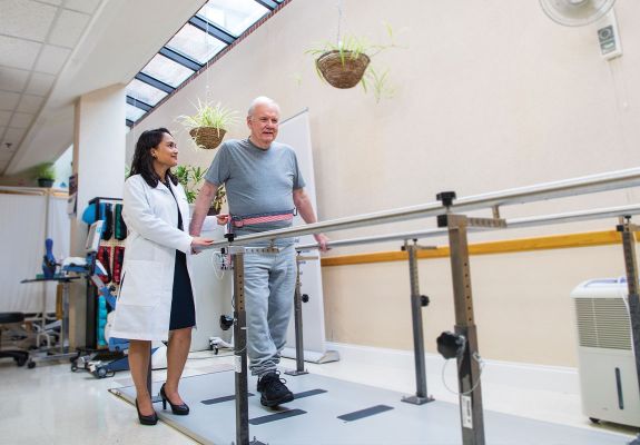 Doctor helping elder with walking strength 