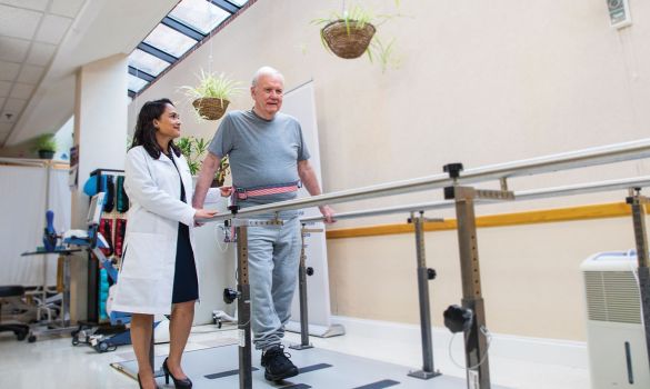 Doctor helping elder with walking strength 